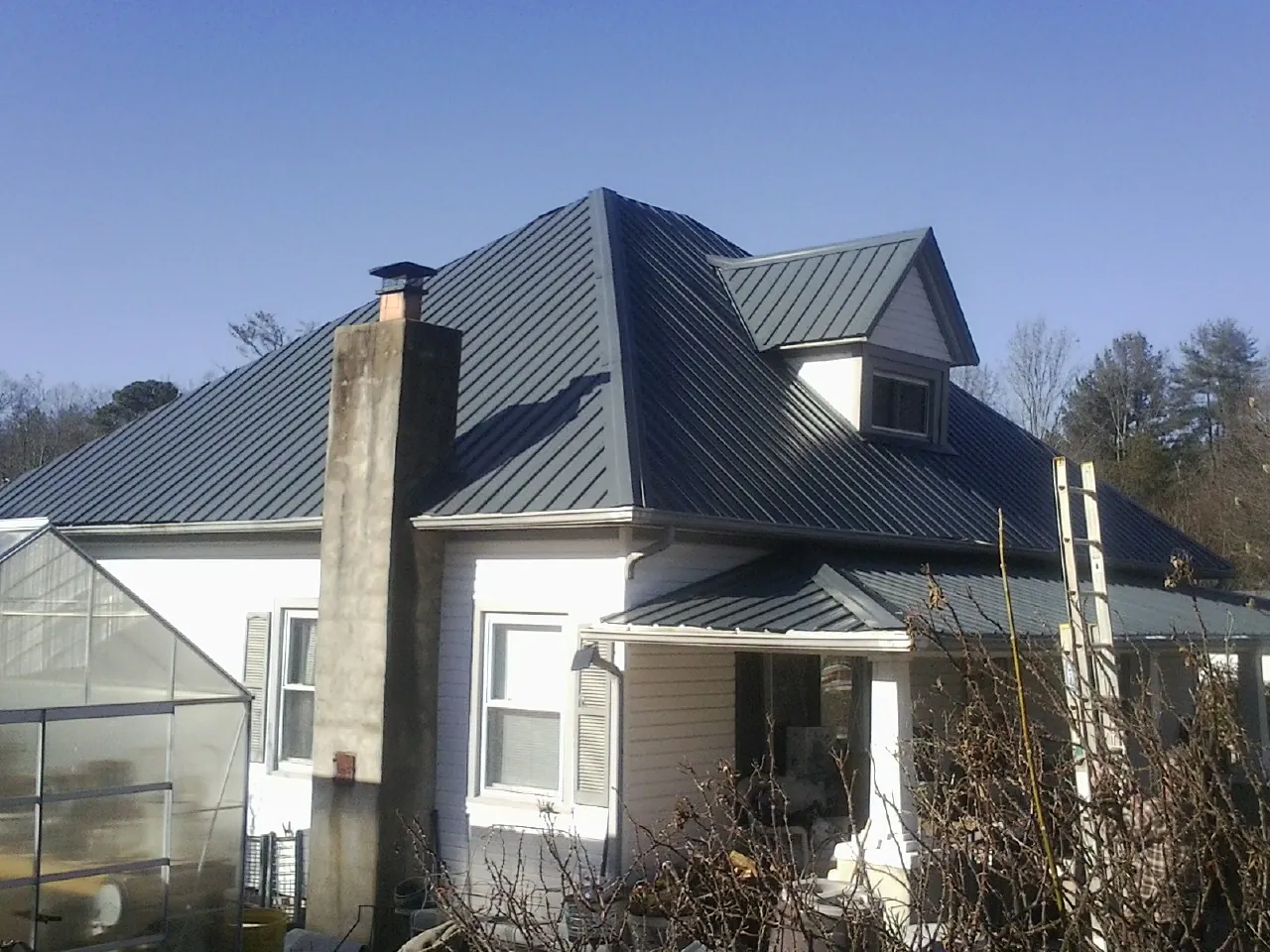 Dark blue standing seam metal roof on a white farmhouse with dormer — Slate & Tile Roof Repair by Roofing Brothers in Waterloo