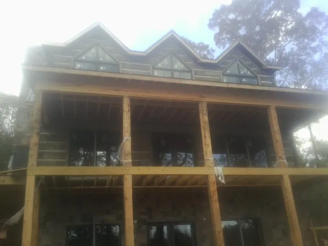Dormers and porch framing on a large log home under construction — Roof Coating work by our crew in Waterloo